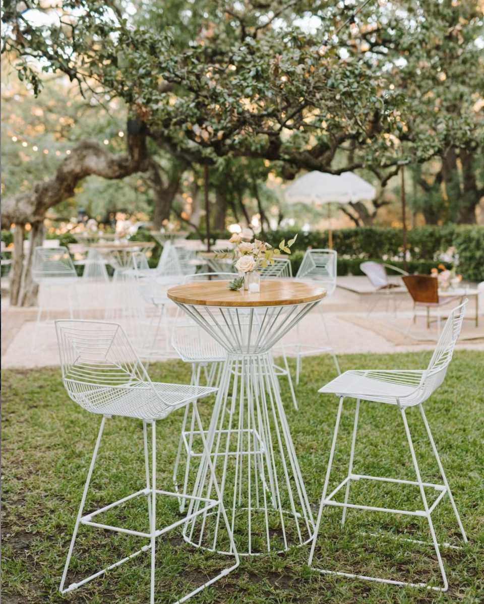 a set of julep white cocktail tables and chairs at an outdoor wedding reception